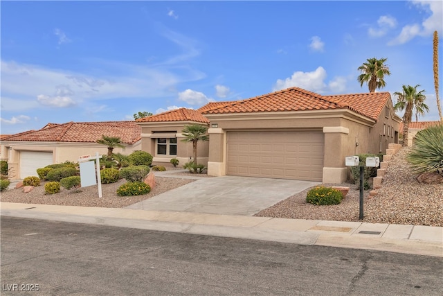 mediterranean / spanish home with stucco siding, a garage, concrete driveway, and a tile roof