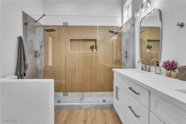 bathroom featuring wood finished floors, a stall shower, and a sink