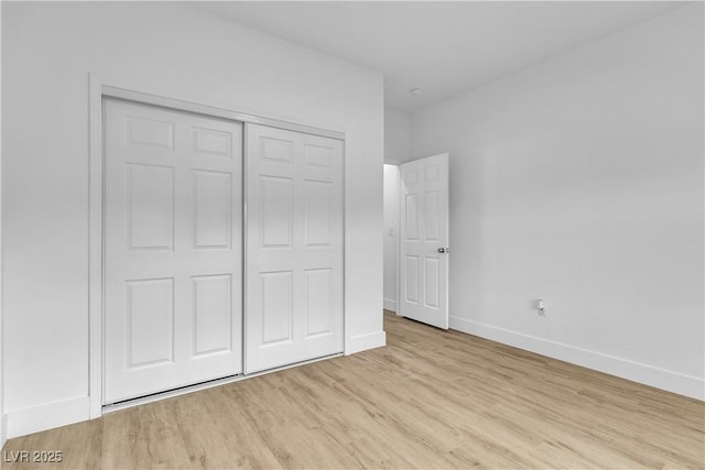 unfurnished bedroom featuring light wood finished floors, a closet, and baseboards