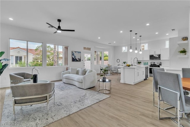 living room with light wood-type flooring, visible vents, recessed lighting, baseboards, and ceiling fan