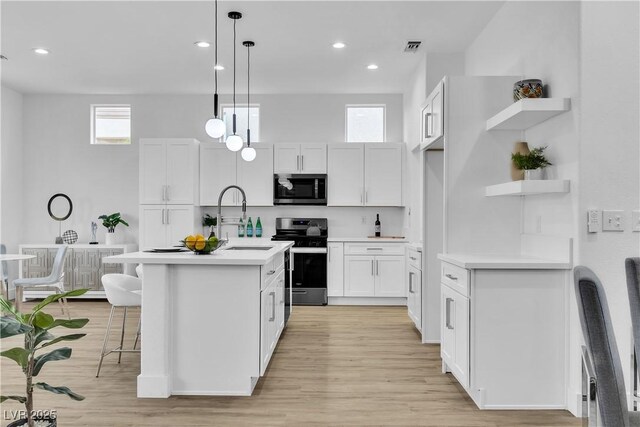 kitchen featuring open shelves, light countertops, appliances with stainless steel finishes, white cabinets, and a sink