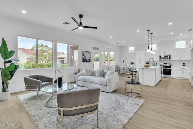 living area with recessed lighting, visible vents, ceiling fan, and light wood finished floors