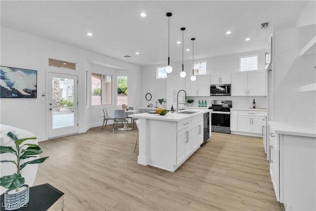 kitchen with stainless steel microwave, visible vents, light countertops, range with gas stovetop, and a sink