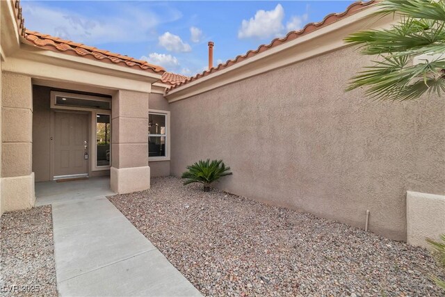 doorway to property featuring stucco siding and a tile roof