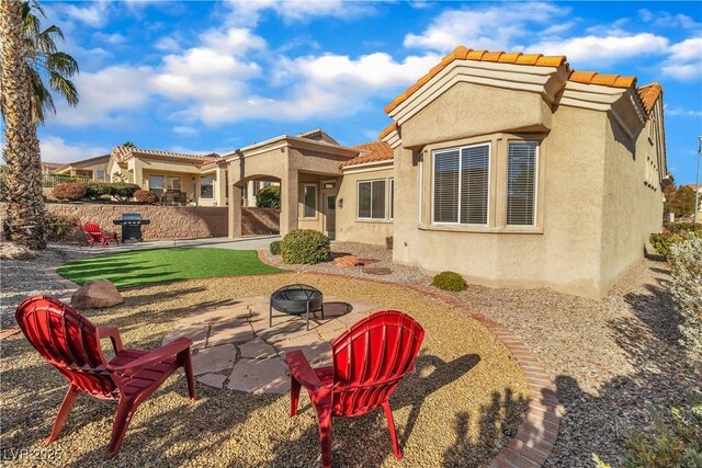 back of house featuring a patio area, a tile roof, stucco siding, and a fire pit