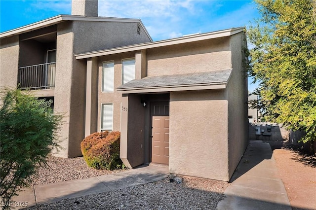 property entrance with a chimney and stucco siding