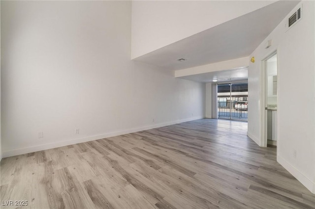 unfurnished room featuring visible vents, baseboards, and wood finished floors