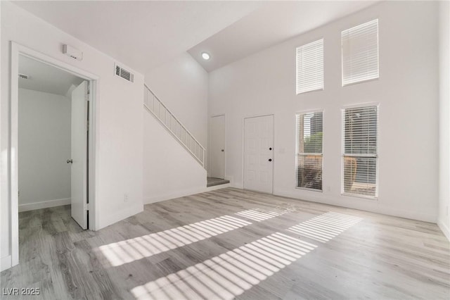 foyer featuring visible vents, stairs, a high ceiling, and wood finished floors