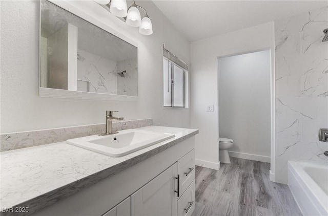 full bath featuring vanity, wood finished floors, baseboards, toilet, and a bathtub