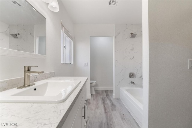 bathroom with visible vents, toilet, wood finished floors, and vanity