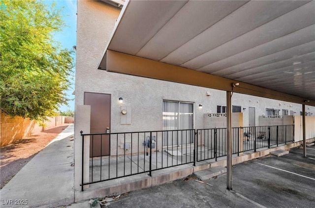 doorway to property featuring fence and stucco siding