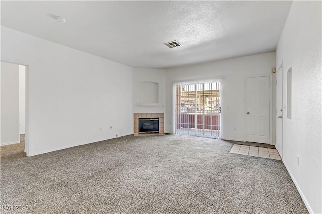 unfurnished living room with visible vents, carpet flooring, a tile fireplace, and a textured ceiling