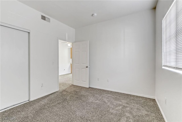 unfurnished bedroom with baseboards, visible vents, carpet floors, and a closet