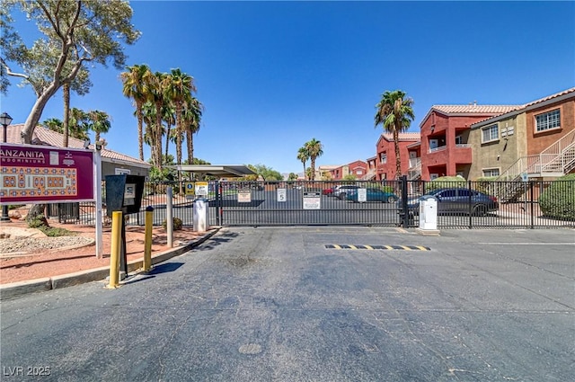 view of street with a gated entry, a residential view, curbs, and a gate