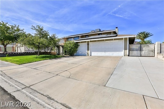 view of front of house with a front lawn, driveway, fence, a garage, and solar panels