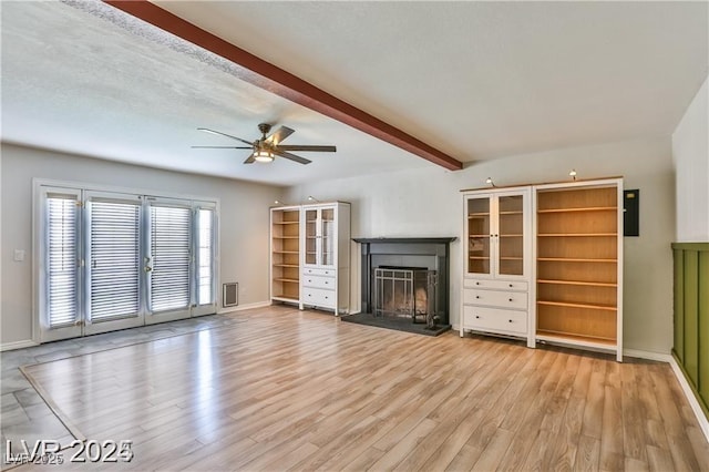 unfurnished living room with light wood-type flooring, beamed ceiling, visible vents, french doors, and a fireplace