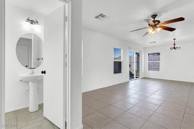 spare room with light tile patterned floors, visible vents, and ceiling fan with notable chandelier