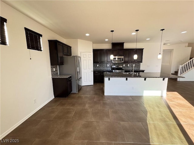 kitchen with a breakfast bar area, backsplash, appliances with stainless steel finishes, and a sink