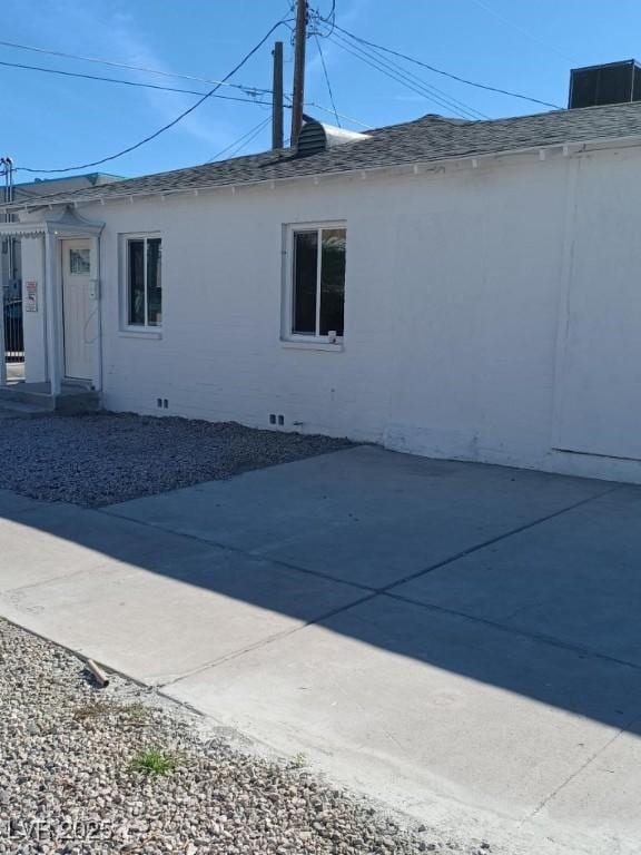 view of property exterior with crawl space, a patio area, and a shingled roof