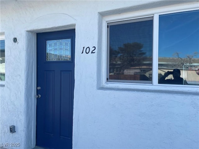 doorway to property featuring stucco siding