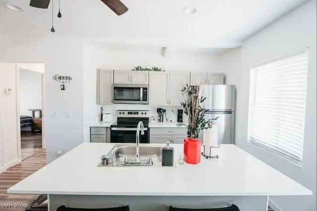 kitchen featuring a center island with sink, a breakfast bar, light countertops, light wood-style floors, and stainless steel appliances