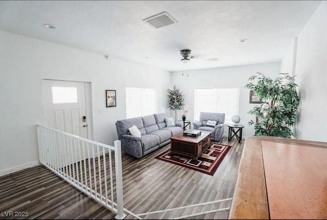 living area featuring visible vents, baseboards, wood finished floors, and a ceiling fan