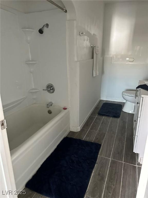 full bath with wood finish floors, toilet, shower / bathing tub combination, baseboards, and vanity