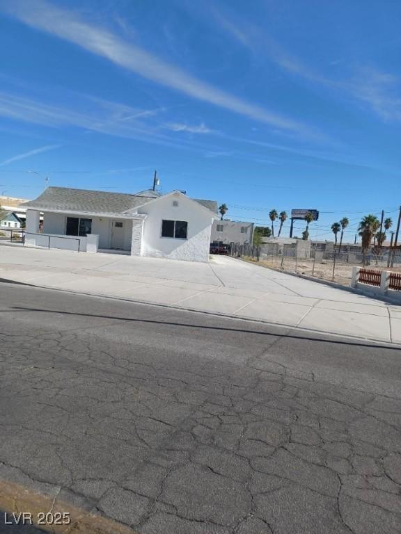 view of front facade featuring concrete driveway and fence