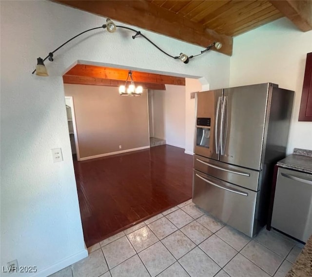 kitchen with beam ceiling, a chandelier, appliances with stainless steel finishes, and light tile patterned flooring