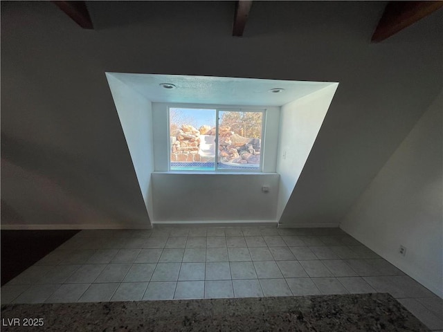 additional living space featuring light tile patterned floors, beamed ceiling, and baseboards