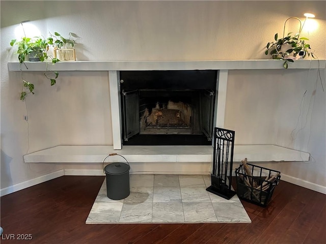 interior details featuring baseboards, wood finished floors, and a fireplace