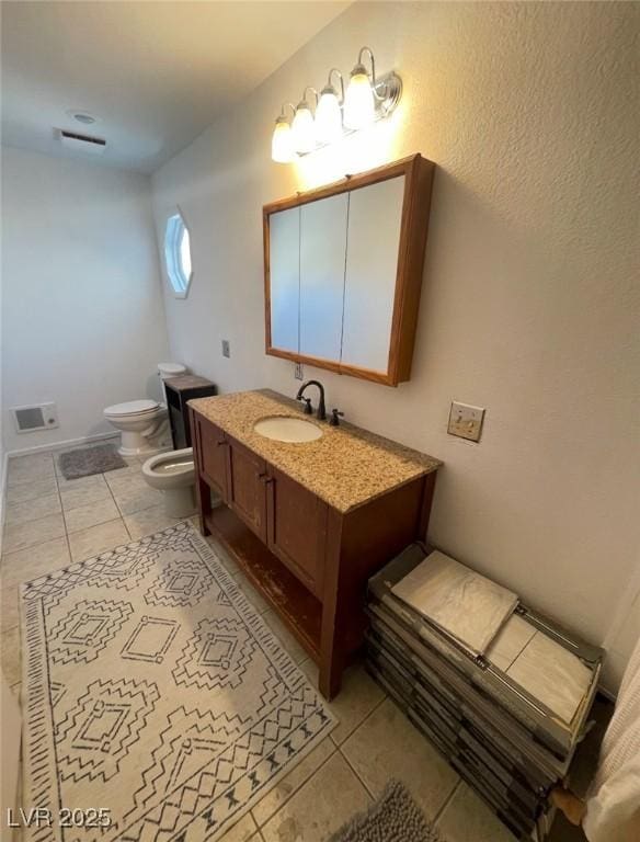 bathroom featuring vanity, a bidet, visible vents, tile patterned flooring, and toilet