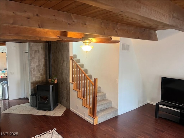 below grade area featuring stairway, wooden ceiling, a wood stove, and wood finished floors