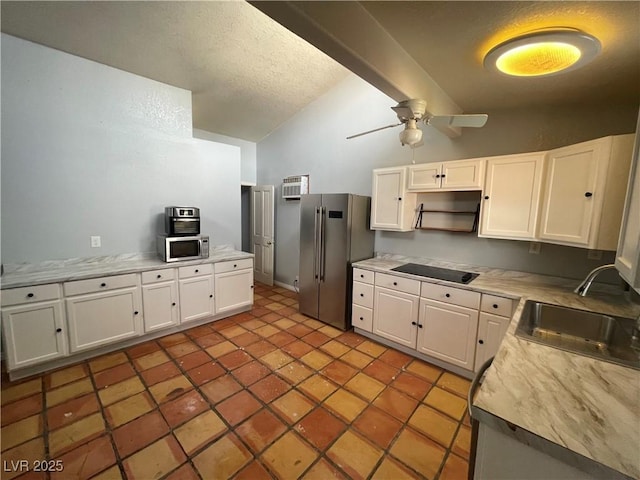 kitchen with white cabinetry, vaulted ceiling, appliances with stainless steel finishes, and a sink