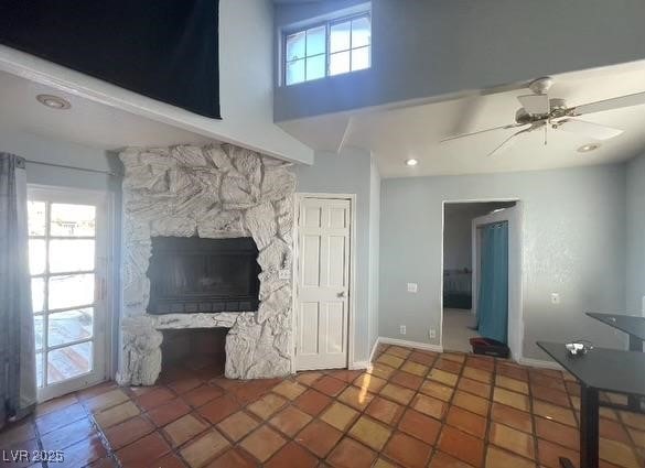 unfurnished living room featuring baseboards, ceiling fan, and a fireplace