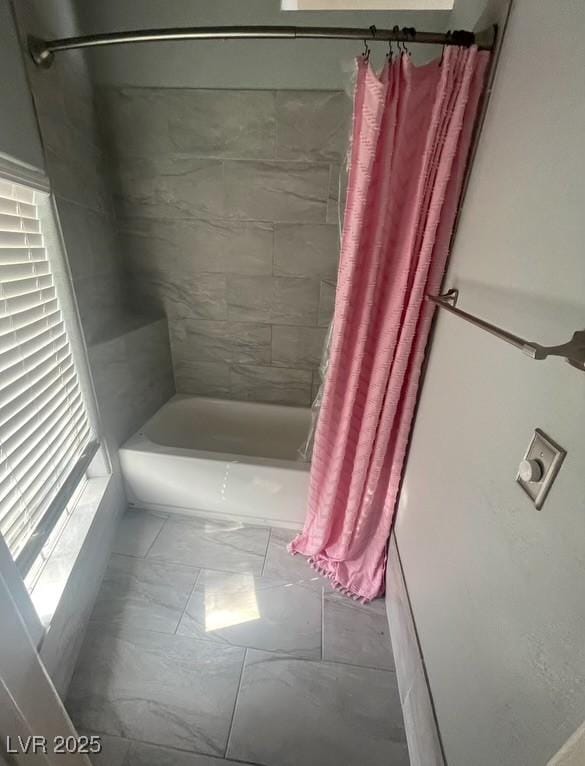 full bath with shower / tub combo with curtain and marble finish floor