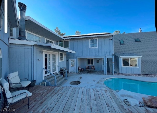 back of property featuring an outdoor pool, a wooden deck, and entry steps