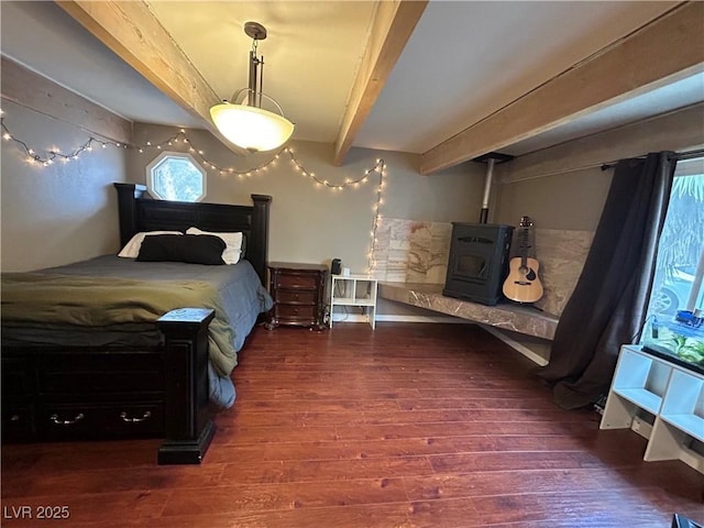 bedroom with beamed ceiling, wood finished floors, and a wood stove