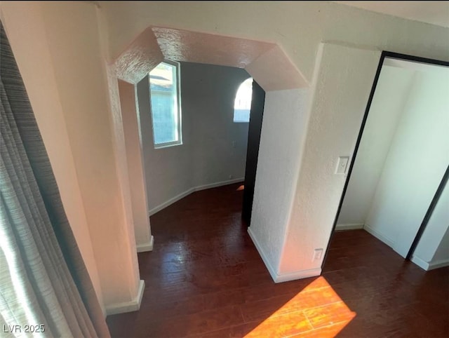 corridor with baseboards, lofted ceiling, and wood finished floors