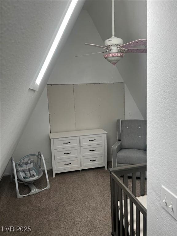 bedroom with a textured wall, vaulted ceiling, ceiling fan, and dark colored carpet