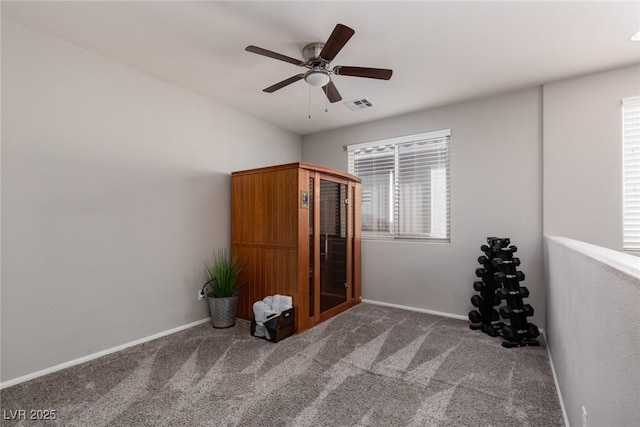 carpeted empty room featuring visible vents, a ceiling fan, and baseboards