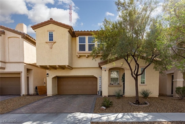 mediterranean / spanish-style house with stucco siding, decorative driveway, a garage, and a tile roof