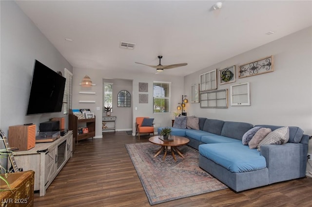 living area with visible vents, baseboards, dark wood-type flooring, and ceiling fan