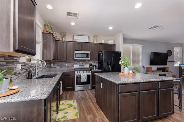 kitchen featuring visible vents, dark wood-style flooring, a sink, dark brown cabinetry, and appliances with stainless steel finishes