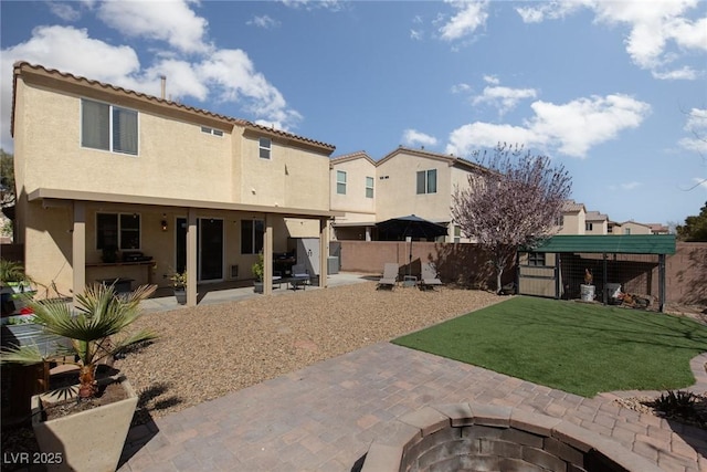 rear view of house featuring fence, an outdoor fire pit, a yard, stucco siding, and a patio area