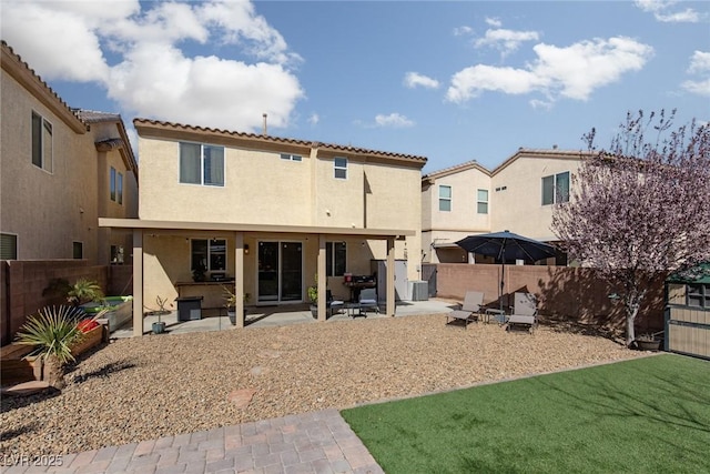 rear view of property with a patio area, stucco siding, and a fenced backyard