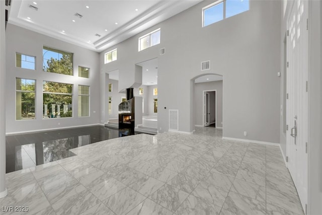 interior space featuring a warm lit fireplace, arched walkways, visible vents, and marble finish floor