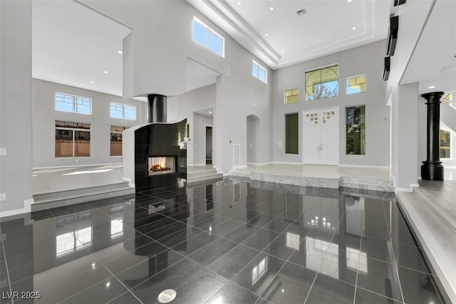 interior space featuring visible vents, baseboards, a high ceiling, recessed lighting, and a multi sided fireplace