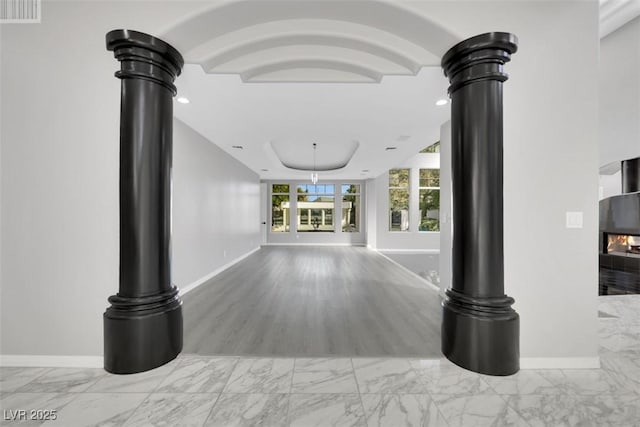 interior space featuring decorative columns, baseboards, marble finish floor, and visible vents