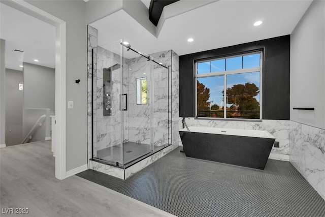 full bath featuring wood finished floors, baseboards, a marble finish shower, a freestanding tub, and recessed lighting